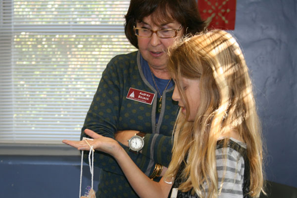 Volunteer docent at the San Mateo County History Museum with a student holding a craft