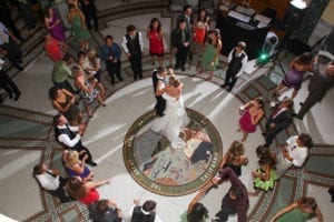 Newlyweds dance in the rotunda of the San Mateo County History Museum with guests dancing around them