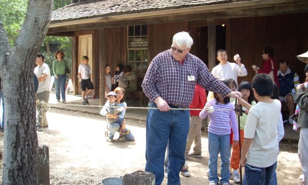 A docent with kids making twine at Rancho Fiesta Day