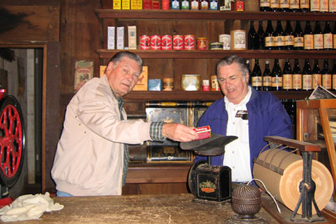 Two volunteers at the Woodside Store weighing a box on an antique scale