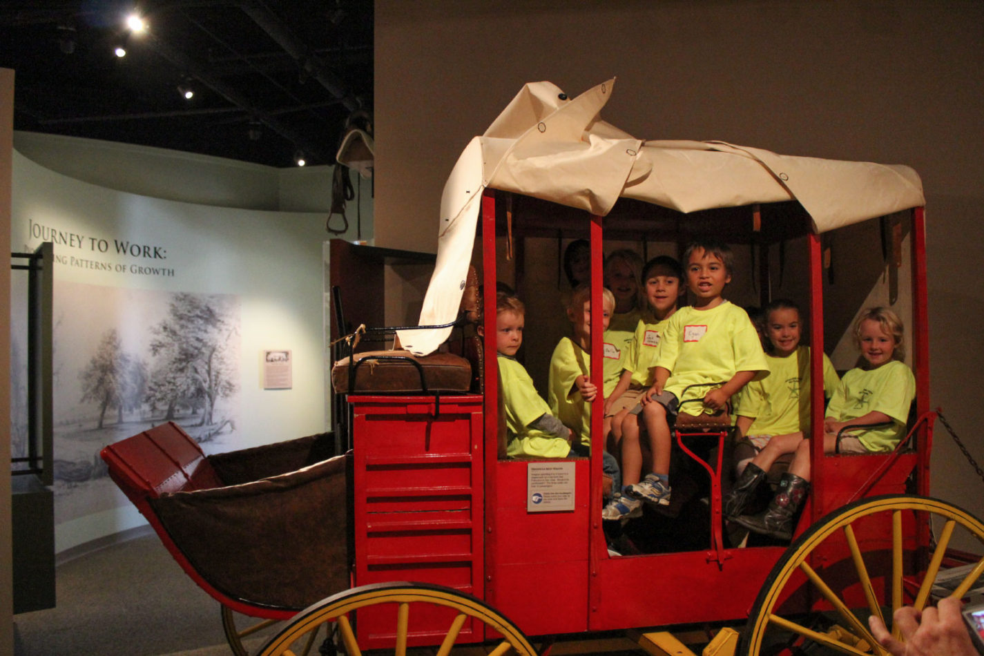 Young students seated in a wagon at the Getting from Here to There school program at the San Mateo County History Museum