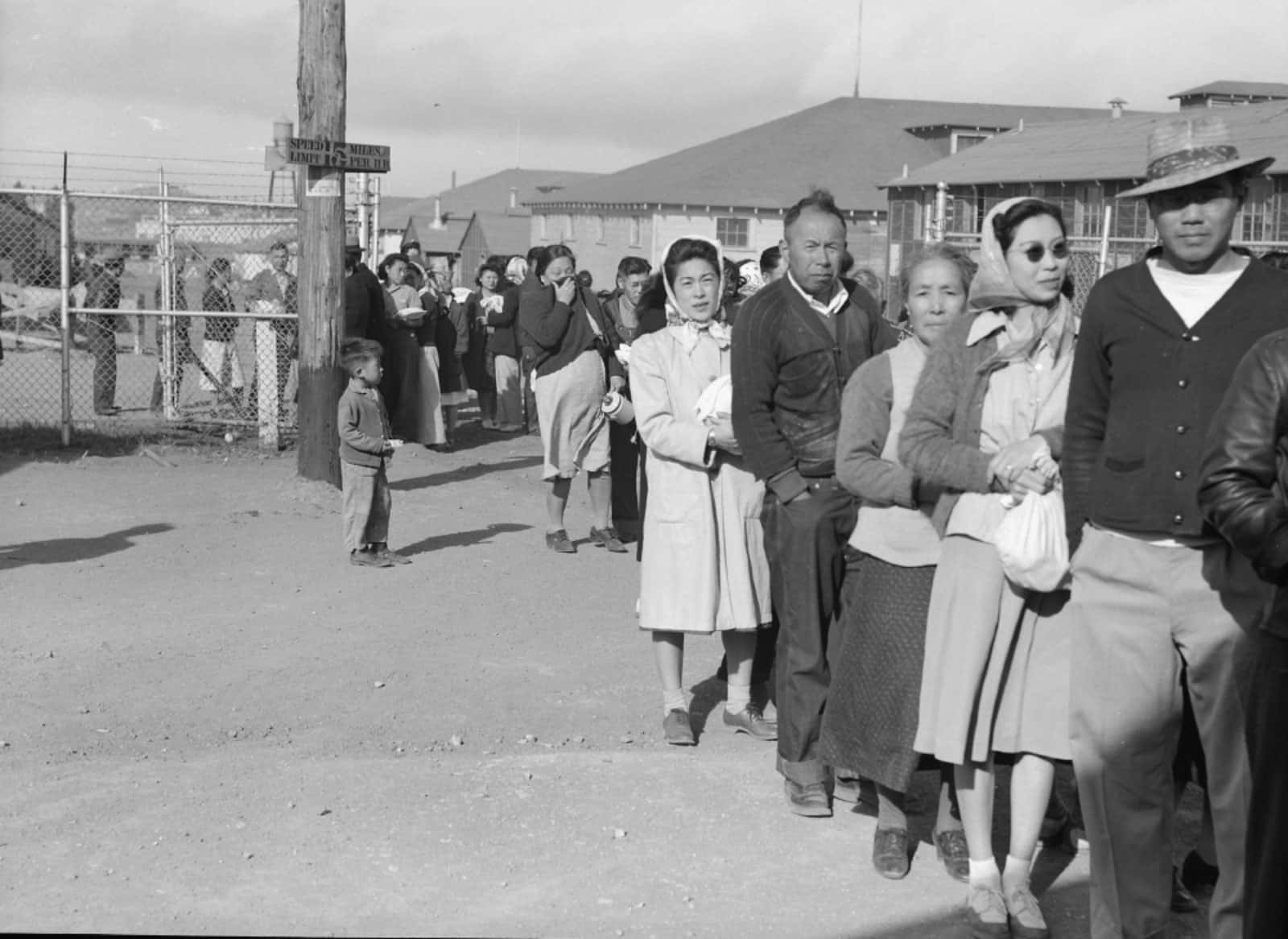 Archival photo of Japanese internment camp waiting in line for a meal