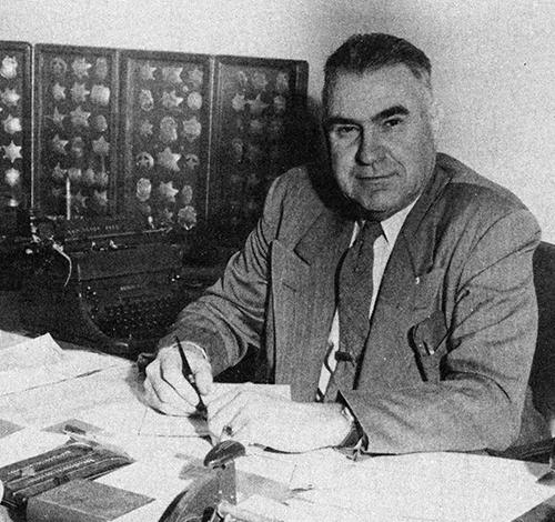 Portrait of Walter Moore in front of his police badge collection