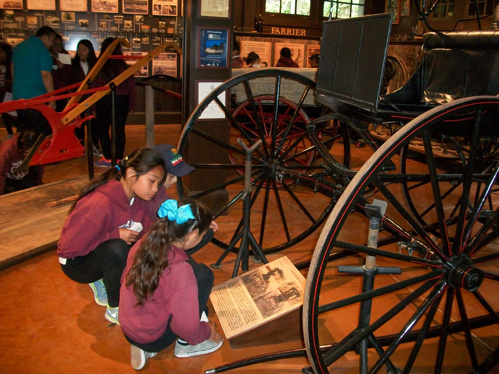 Students at the Folger Stable school program reading a display for a horse buggy