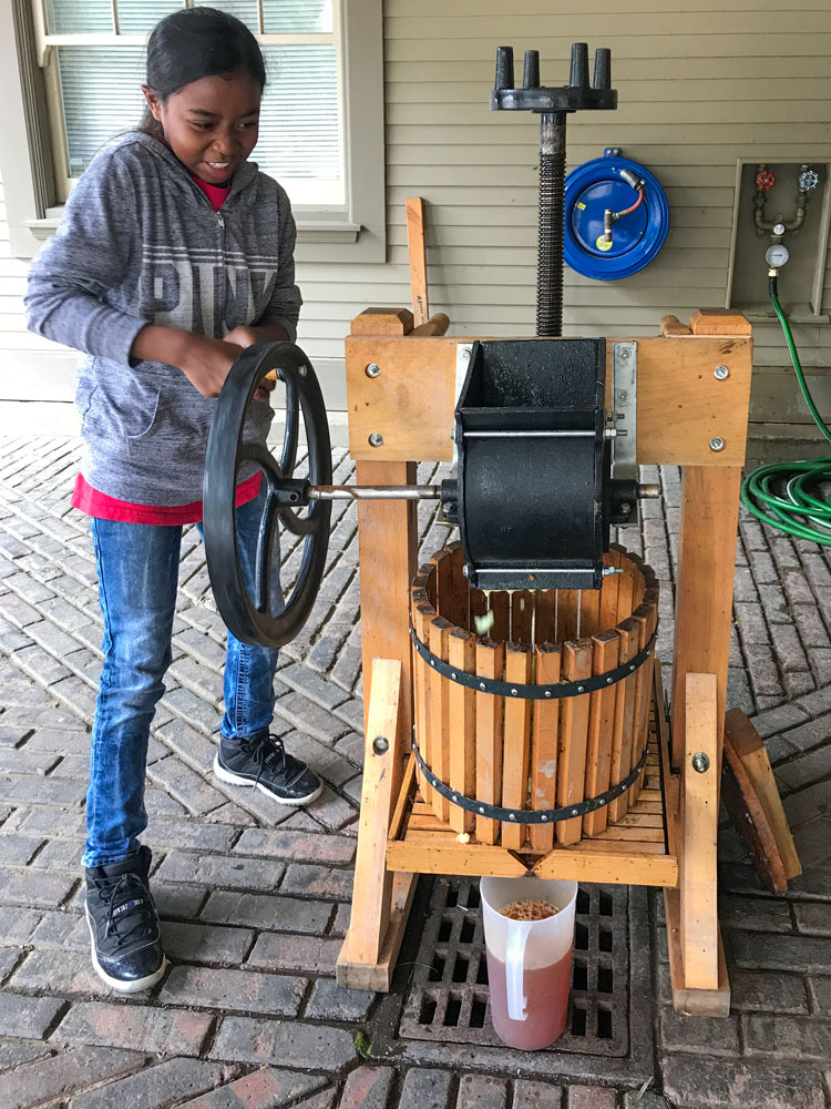 A student at the Folger Stable school program makes apple juice in an old fashioned press