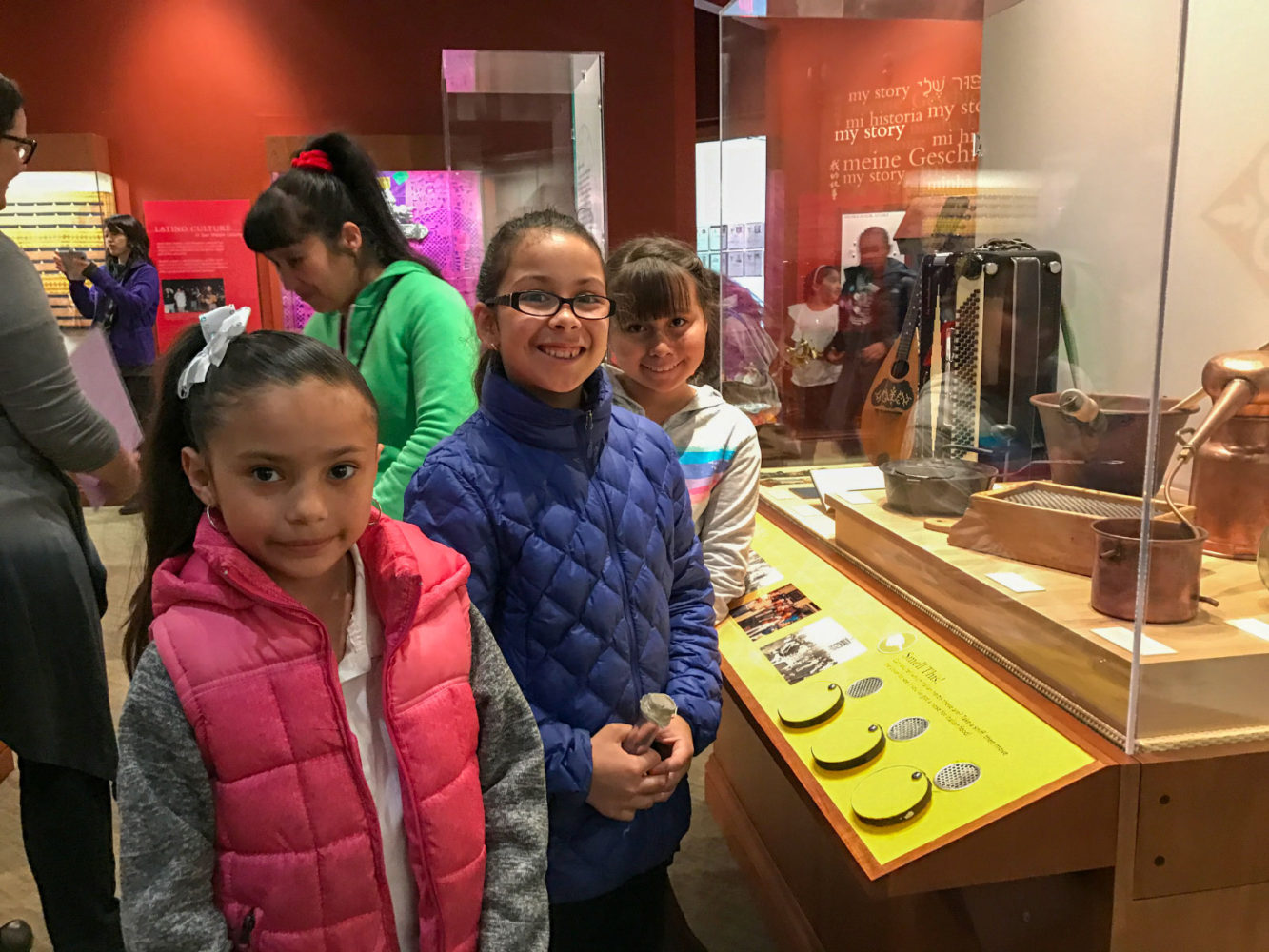School children pose in front of a museum display from People from Many Places at the San Mateo County History Museum