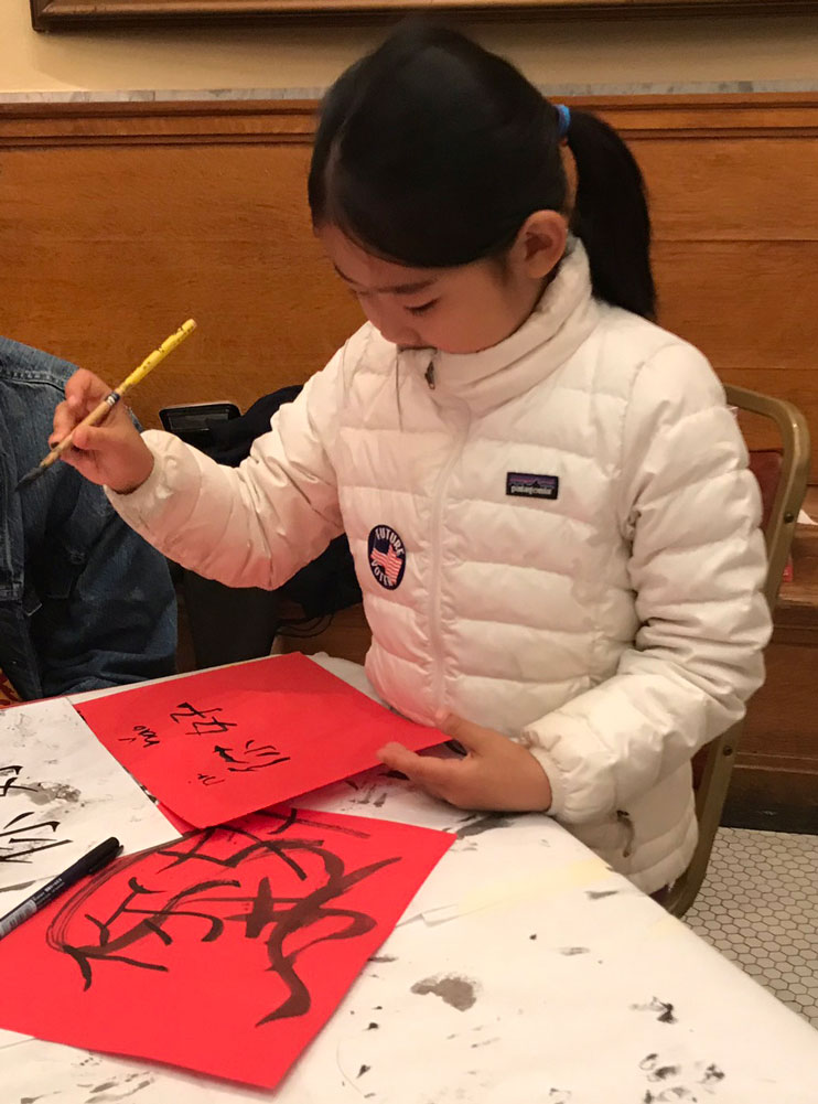 A young girl writes chinese calligraphy at Lunar New Year celebration at the San Mateo County History Museum