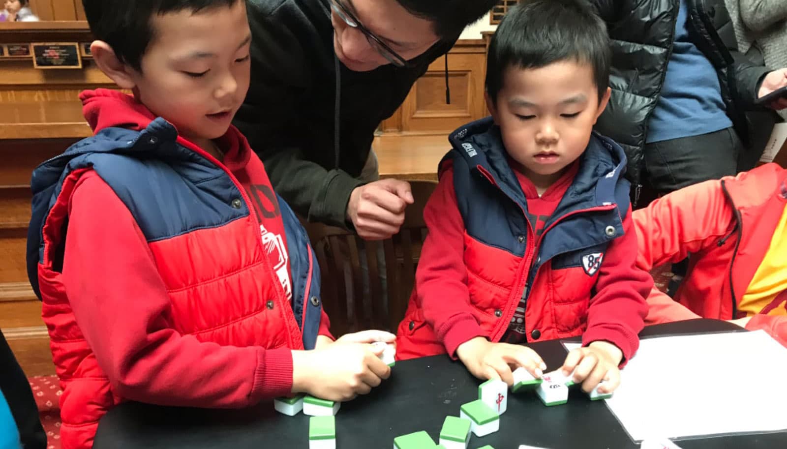 Two young boys learn mahjong at the lunar new year celebration at the San Mateo County History Museum