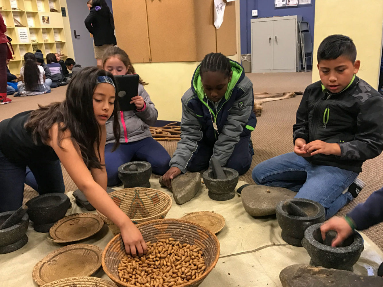 Students use a mortar to ground acorns at Providing Plenty school program at the San Mateo County History Museum
