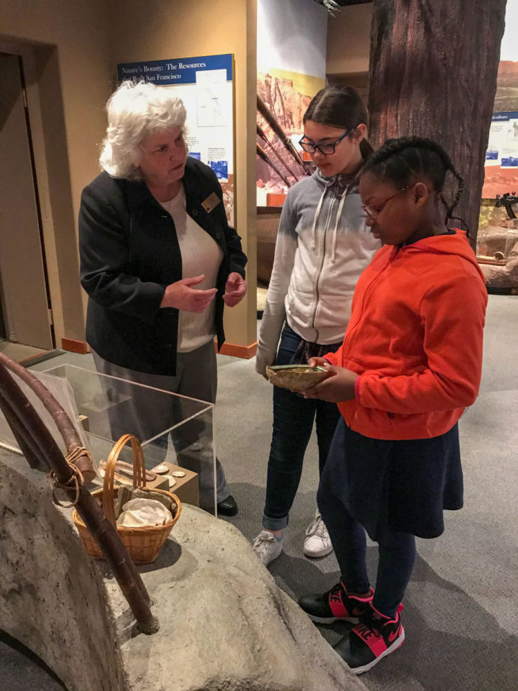 Students view a display with a staff member at Providing Plenty school program at the San Mateo County History Museum