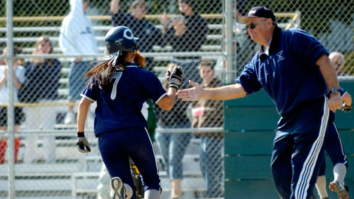Girls softball coach Jim Liggit congratulates a softball player as she crosses home plate
