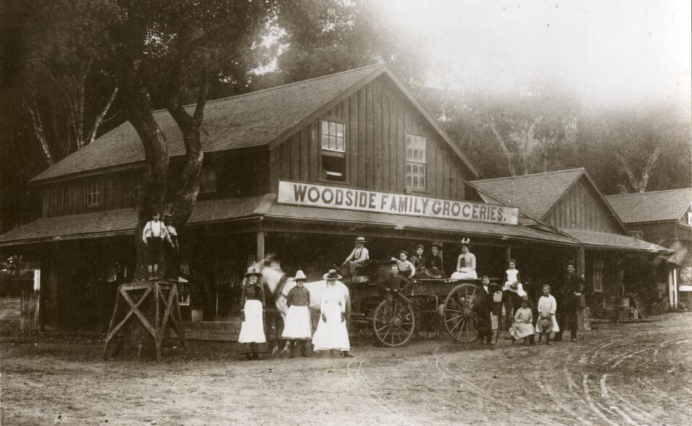 Archival photo of Woodside Family Groceries with family posing in front on horse drawn wagon 1854