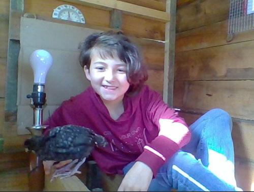 Young girl sitting in a coop with her chick