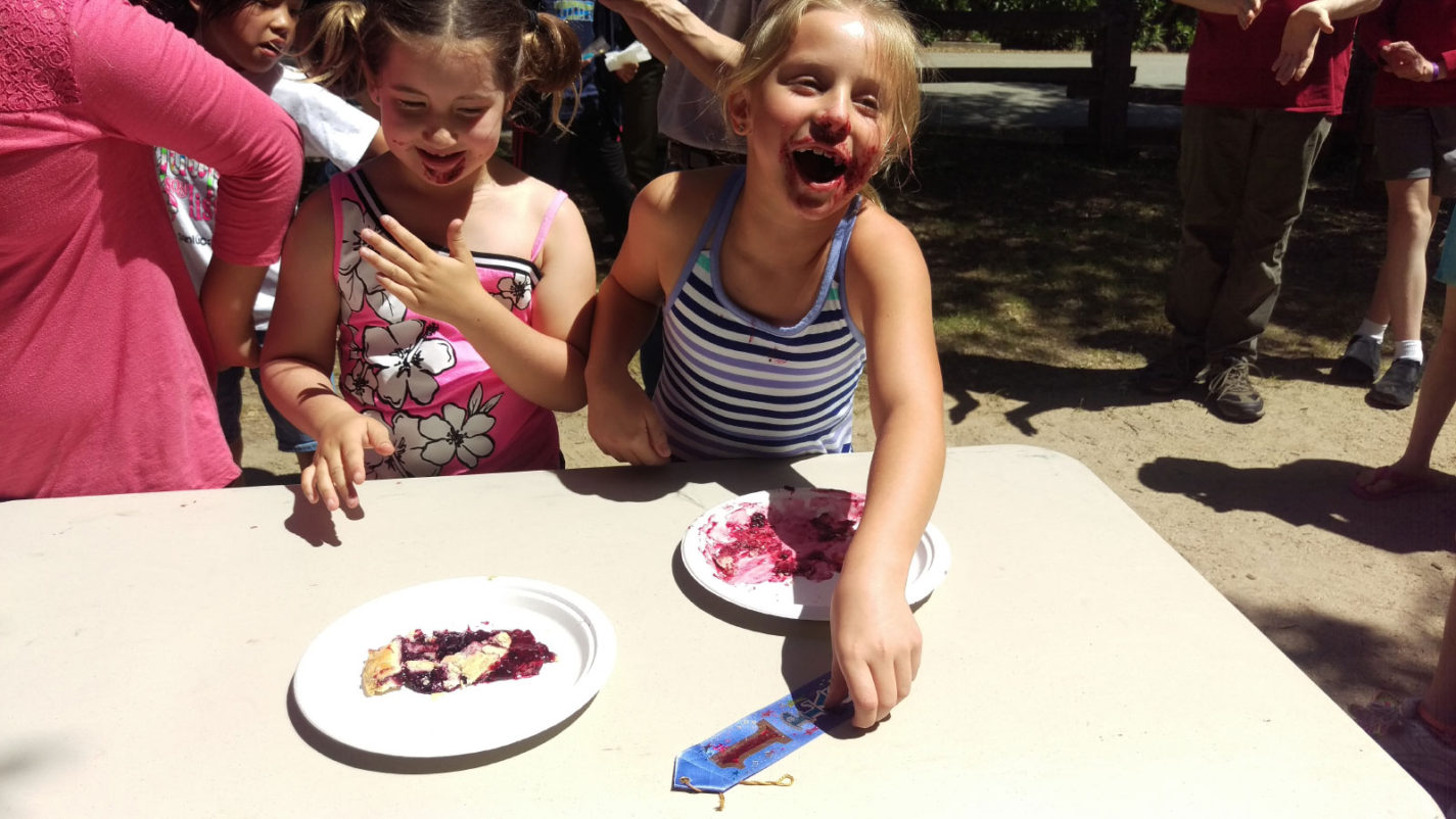 Two young girls eat pie at the Old Woodside Store Day