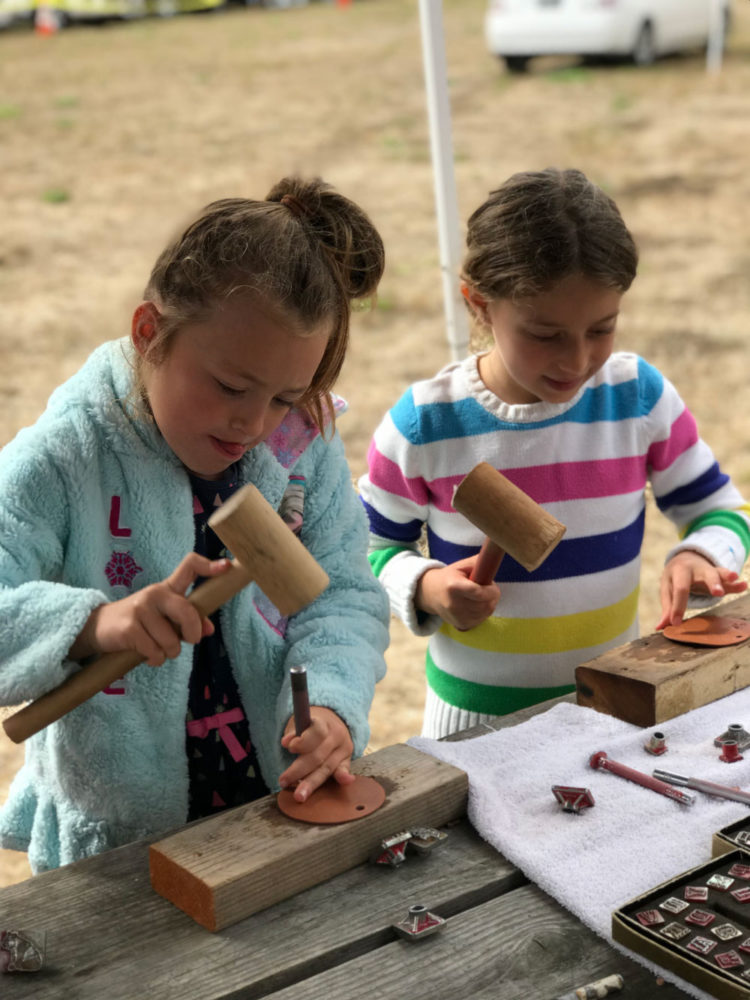 Two young girls work on a craft at Rancho Fiesta Day at Sanchez Adobe