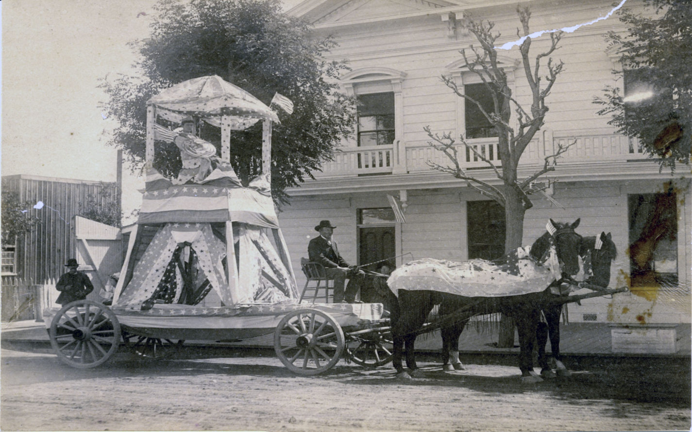 Young woman with a crown on July Fourth Float pulled by horses in front of the Tremont House on Main Street in Redwood City circa 1880s