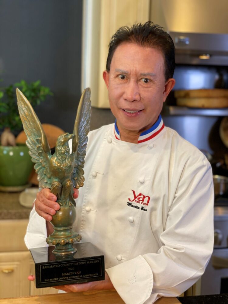 Chef Martin Yan in his kitchen holding the San Mateo County History Makers eagle award
