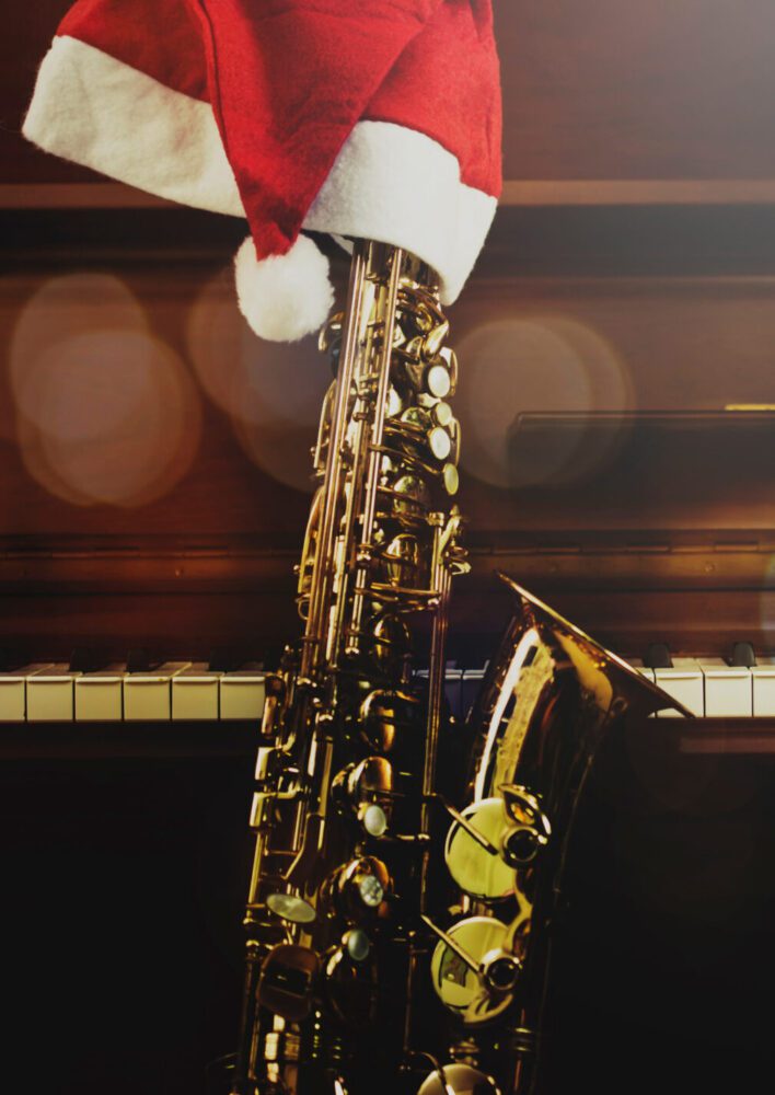 Saxophone with Santa hat leaning against a keyboard
