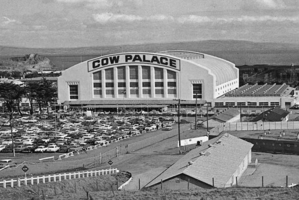 Exterior view of the Cow Palace with many cars parked in front circa 1950s